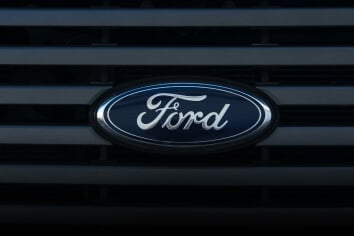 A Ford badge on the front of a black car.