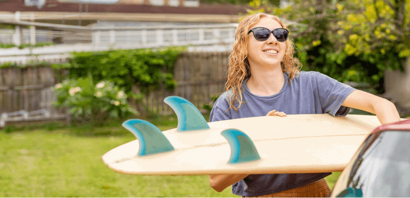 Girl loading surfboard into the car