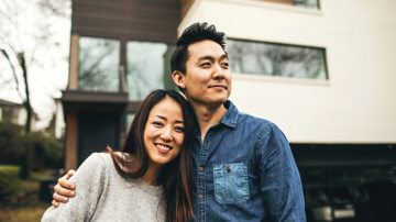 A couple posing in front of their house after purchasing contents-only insurance