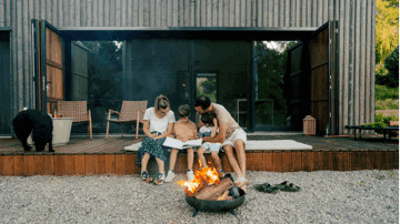 A family sitting by the fire in their backyard