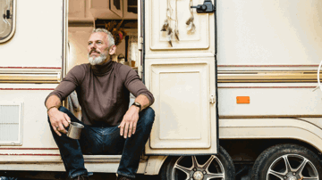 A man enjoying a cup of coffee sitting in the doorway of his new motorhome