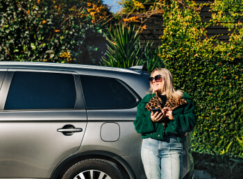 Leopard lady standing next to her car.